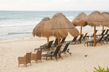 Wicker and Rattan Chairs Under Thatched Huts on Beach clipart