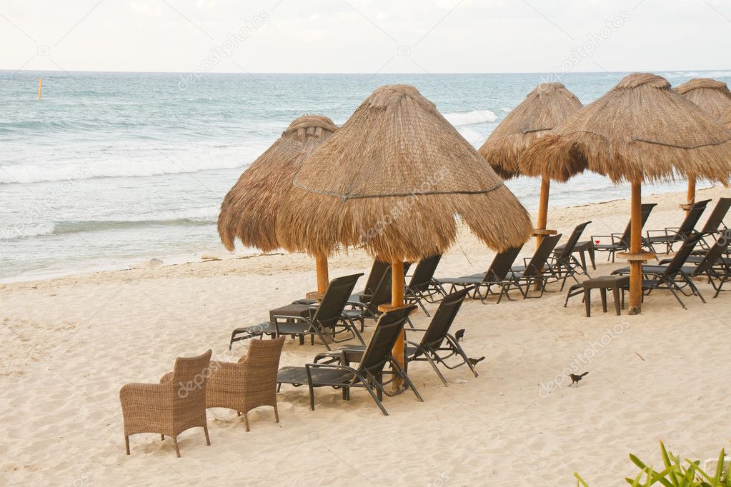 Wicker and Rattan Chairs Under Thatched Huts on Beach