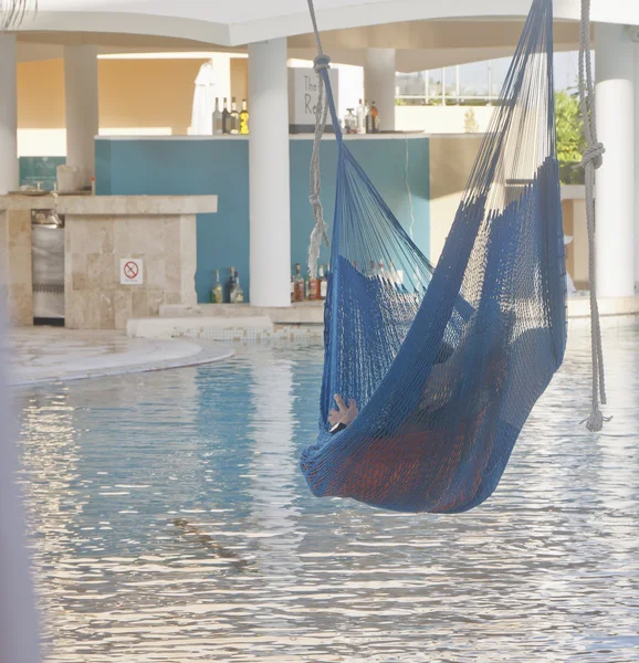 Persona en la hamaca de la piscina con la barra de la piscina en fondo — Foto de Stock