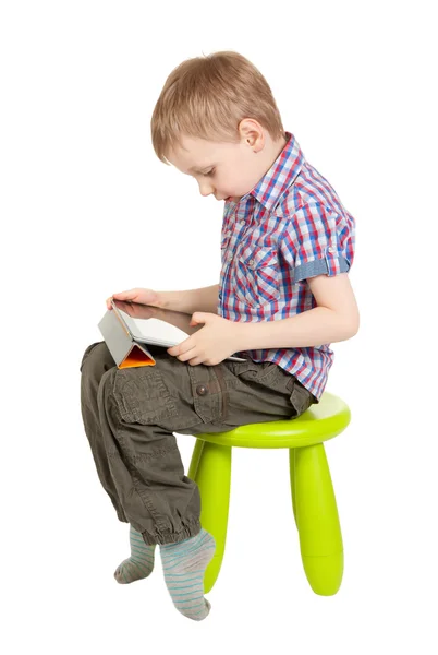 Junge mit Tablet-PC sitzt auf grünem Kinderstuhl — Stockfoto