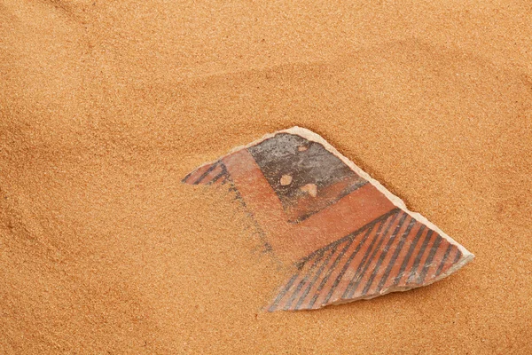 stock image Anasazi pottery shard in red sand