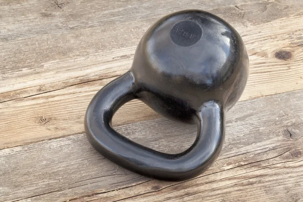 Μαύρο kettlebell στο ξύλινο κατάστρωμα — Φωτογραφία Αρχείου