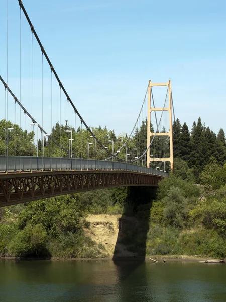 Puente colgante a pie que atraviesa el cielo azul del río —  Fotos de Stock