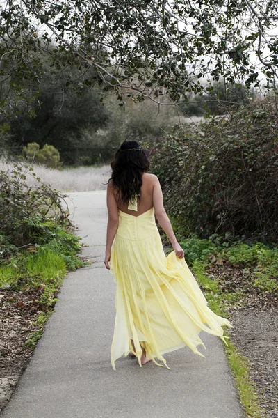 Ung kvinna gå i gul klänning utomhus — Stockfoto