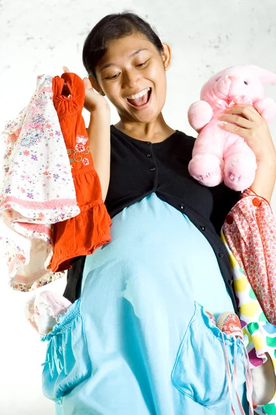 Mulher grávida feliz com roupas de bebê e boneca de coelho — Fotografia de Stock