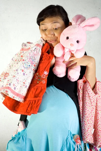Mujer embarazada con ropa de niño y muñeca de conejo — Foto de Stock