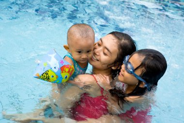 Asian mother and children swim together clipart