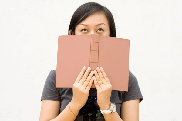 Female student cover face with book — Stock Photo, Image
