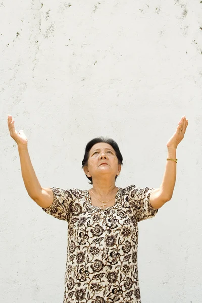 Yaşlı kadın ibadet eller yükselterek — Stok fotoğraf