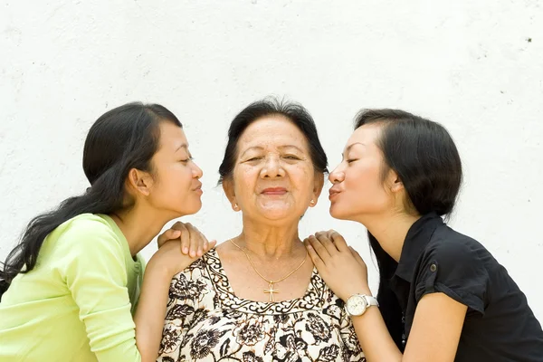 Two granddaughter kiss their old grandmother — Stock Photo, Image