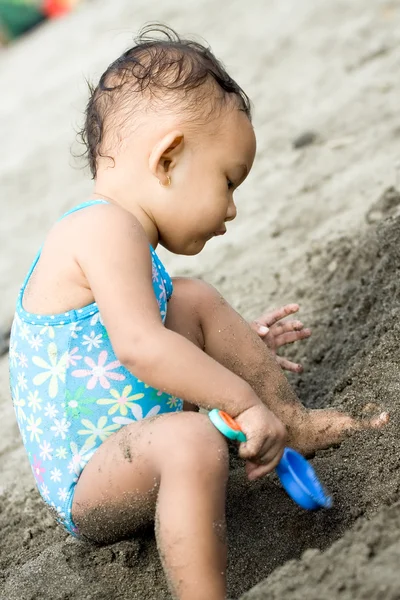 Ethnic toddler girl play with beach sand — Stock Photo, Image