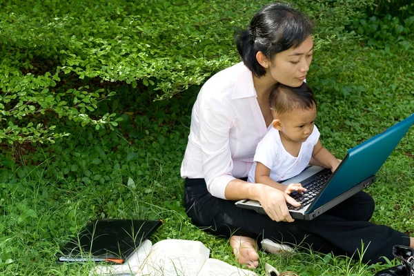 Pracující matka a dítě před přenosný počítač — Stock fotografie