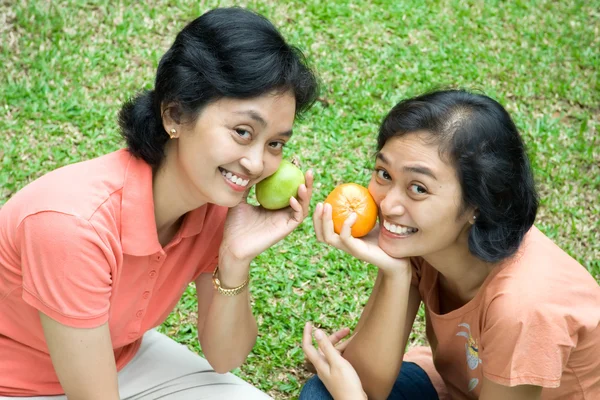 Two asian sisters with fruits on hand — Stock Photo, Image