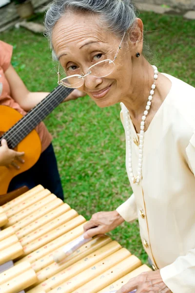 Mulher sênior tocando música com a família — Fotografia de Stock