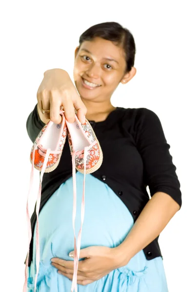Беременная женщина с парой детских туфель — стоковое фото
