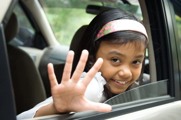 Child waving goodbye from inside a car — Stock Photo, Image