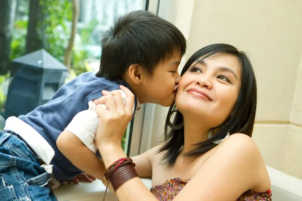 Азиатский мальчик целует мать — стоковое фото