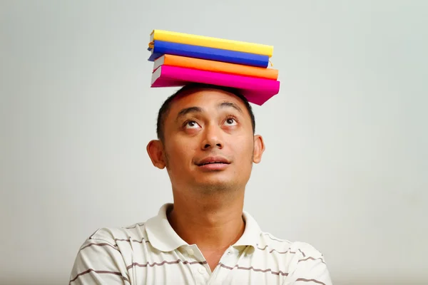 Etnische jongeman met boeken op hoofd — Stockfoto