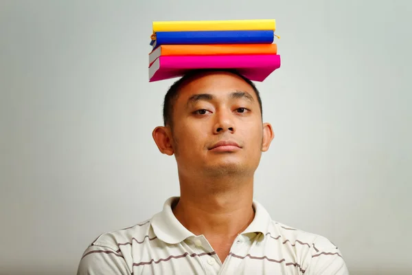 Junger Mann balanciert Bücher auf dem Kopf — Stockfoto