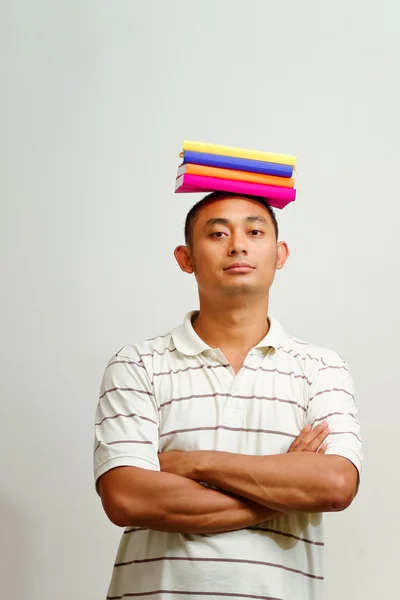 Asian young man with books on head — Stock Photo, Image