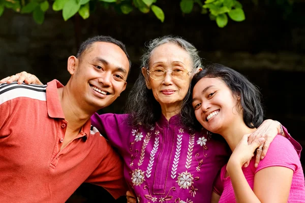 Счастливый азиатский молодой человек и женщина обнимают старую мать — стоковое фото