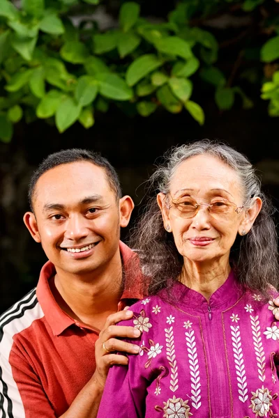 Счастливый азиатский молодой человек обнимает пожилую мать — стоковое фото