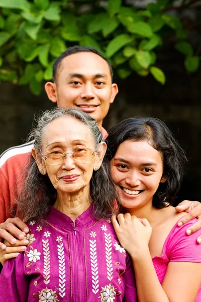 Ευτυχής ασιατικές νεαρός άνδρας και γυναίκα αγκαλιάσει παλιά μητέρα — Φωτογραφία Αρχείου