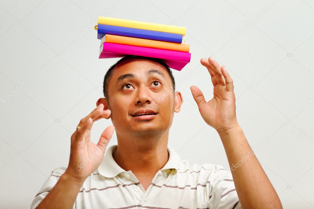 Ethnic young man balancing books on head