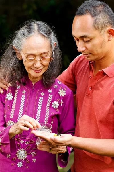 Asian young man help elderly woman taking medicine — Stock Photo, Image