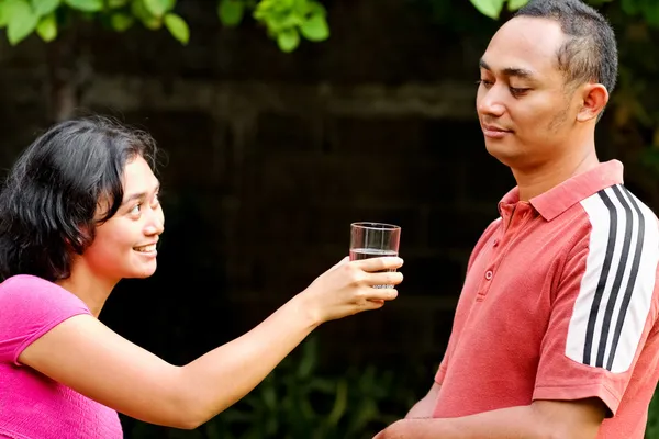 Etniska ung kvinna erbjuder ren mineralvatten till manlig vän — Stockfoto