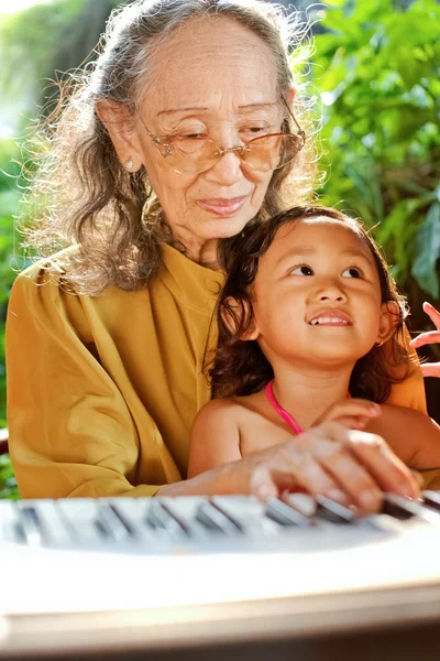 Етнічна дитина і бабуся грають на піаніно — стокове фото