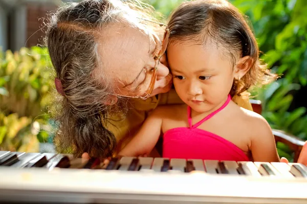 Ethnic child and grandma playing piano together — Stock Photo, Image