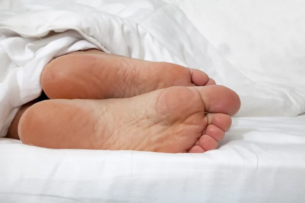 stock image Close up of feminine feet in a bed