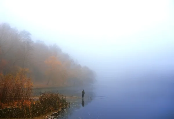 stock image A fisherman on a misty lake