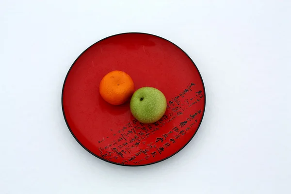 Яблоко и мандарин на тарелке — стоковое фото