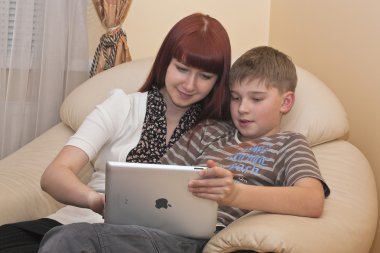 Two children looking at an iPad2 screen clipart