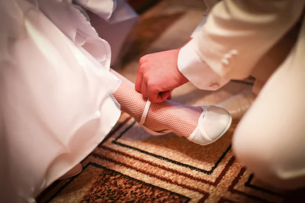 Ženich je pomáhá nosit na nevěstě bílé boty — Stock fotografie