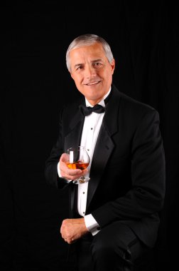 Middle aged man wearing a tuxedo with brandy snifter clipart