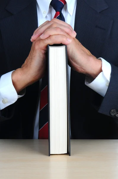 Крупный план бизнесмена, опирающегося на книгу за столом — стоковое фото