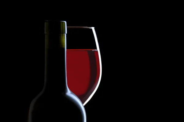 Copo de vinho tinto e garrafa em preto — Fotografia de Stock