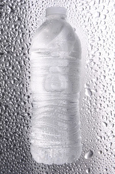 Бутылка воды на влажной металлической поверхности — стоковое фото