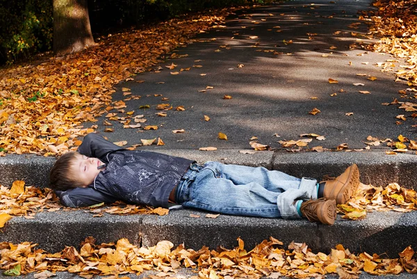Kind im fallenden Herbstlaub. — Stockfoto
