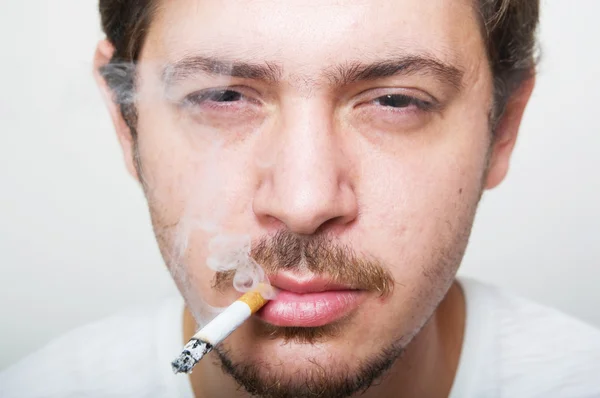 该名男子手持在他嘴里的香烟 — 图库照片
