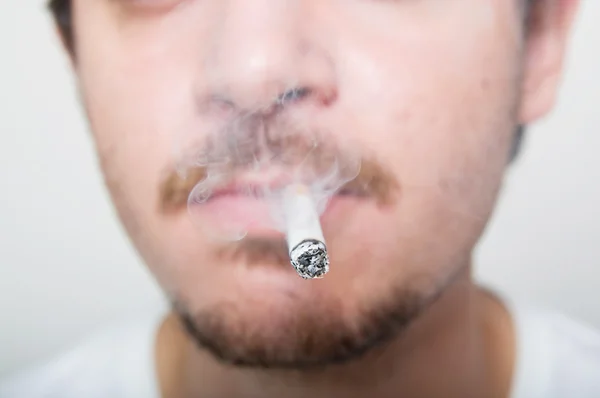 该名男子手持在他嘴里的香烟 — 图库照片