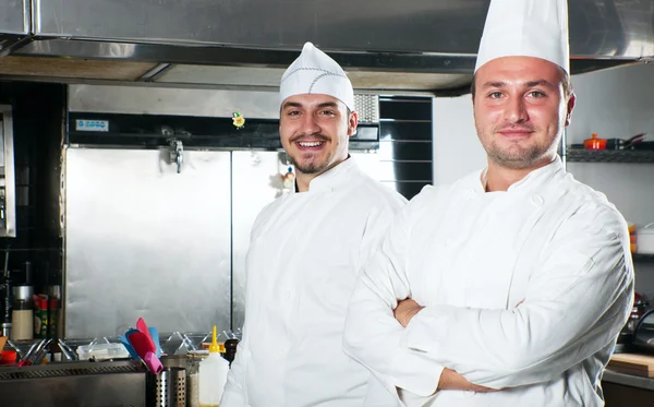 Portrét dvou kuchařů, usmíval se a drží kuchyňské nádobí — Stock fotografie