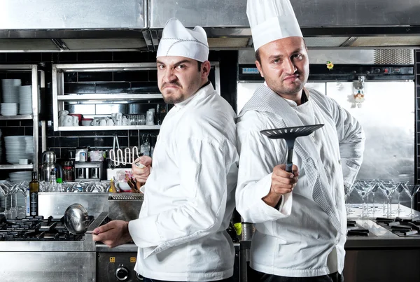 Portrait of two chefs smiling and holding kitchen utensil — Stock Photo, Image