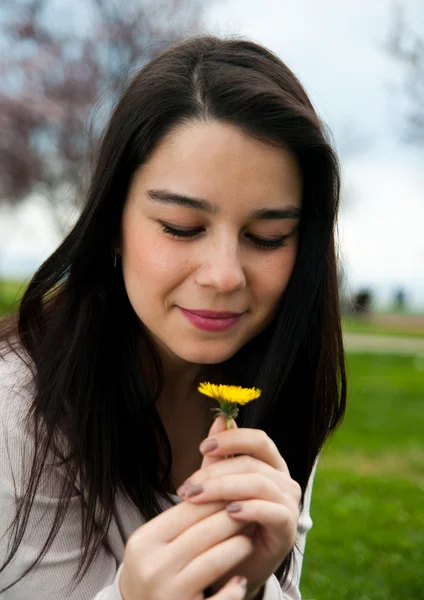 Retrato de uma jovem mulher bonita feliz segurando uma flor — Fotografia de Stock