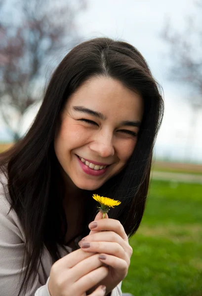 Πορτρέτο του ένα ευτυχισμένο όμορφο νεαρό θηλυκό κρατώντας ένα λουλούδι — Φωτογραφία Αρχείου