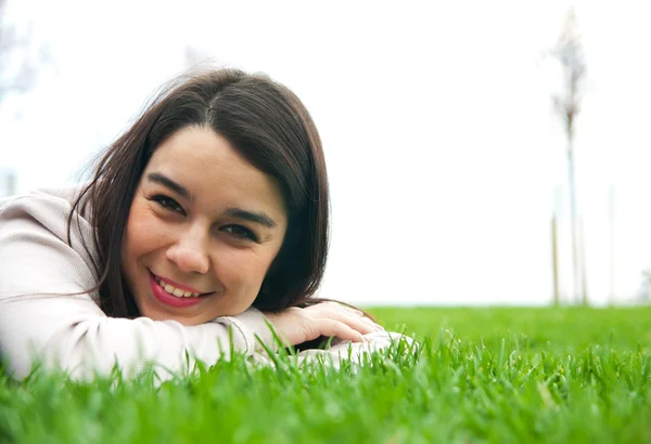 Krásná mladá žena ležící na trávě — Stock fotografie