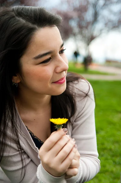 Porträtt av en glad vackra unga kvinna som håller en blomma — Stockfoto